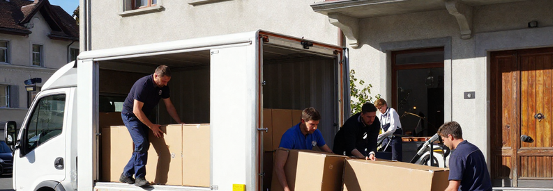 Équipe de déménageurs professionnels chargeant mobilier et cartons dans un camion devant un immeuble de Kriens