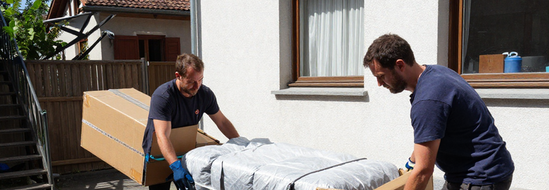 Déménageurs professionnels à Wohlen portant meubles et cartons dans un immeuble résidentiel