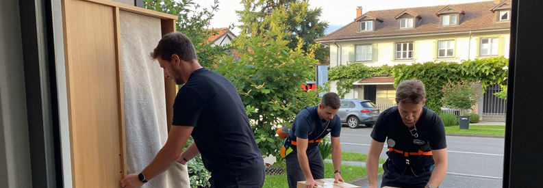 Équipe de déménageurs professionnels emballant meubles et cartons dans un appartement à Uster, illustrant les services complets d'emballage et transport.